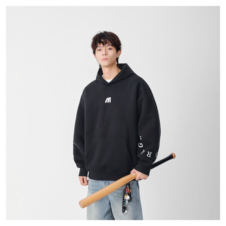 Model in a black hoodie with white chest logo and sleeve lettering, holding a wooden bat, with light blue jeans