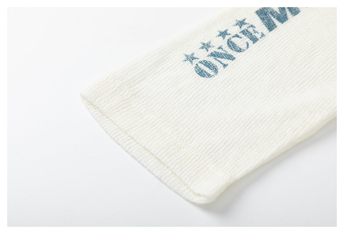 Close-up of the ivory knit sleeve hem with part of a blue star-and-letter print.