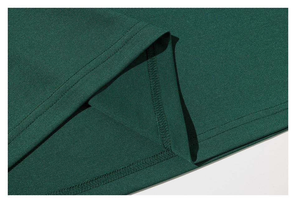 Close-up of dark green garment fabric showing a folded edge and overlock stitching.