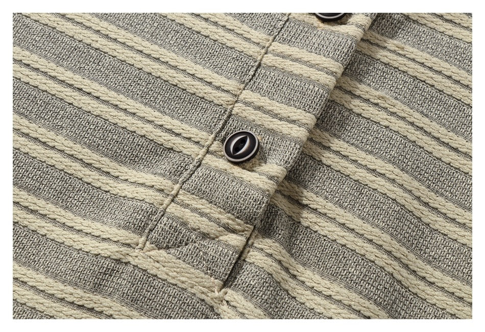 Close-up of a dark button and placket on gray-beige knit fabric with raised cream stripes.
