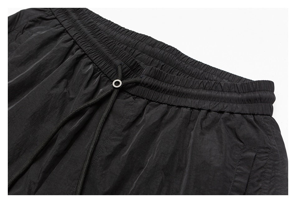Close-up of a black garment's gathered elastic waistband, drawstring, and metal eyelet.