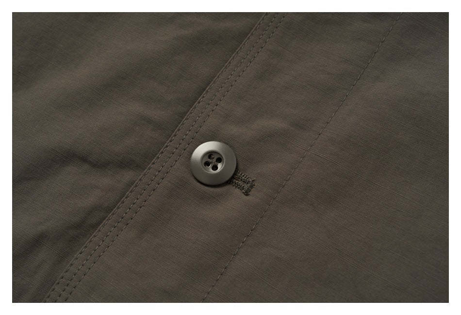 Close-up of a dark four-hole button and stitched buttonhole on the brown jacket fabric.