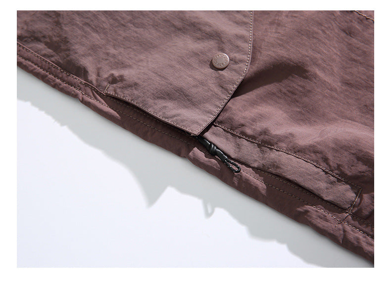 Close-up of brown shorts showing a buttoned flap and a small zipper with a pull tab along the seam.