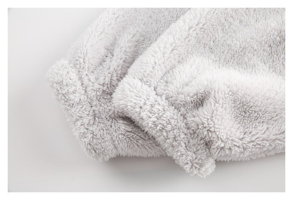 Close-up of pale gray plush fabric folded to show its thick, fluffy pile and finished edge.