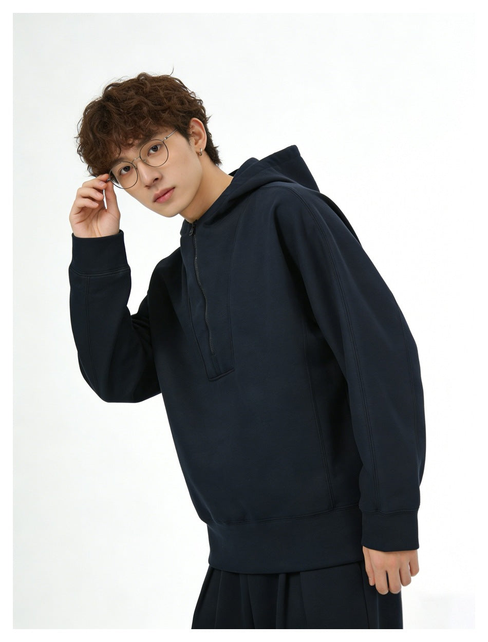Model wearing a dark navy hooded pullover with a short front zipper, shown at an angle.