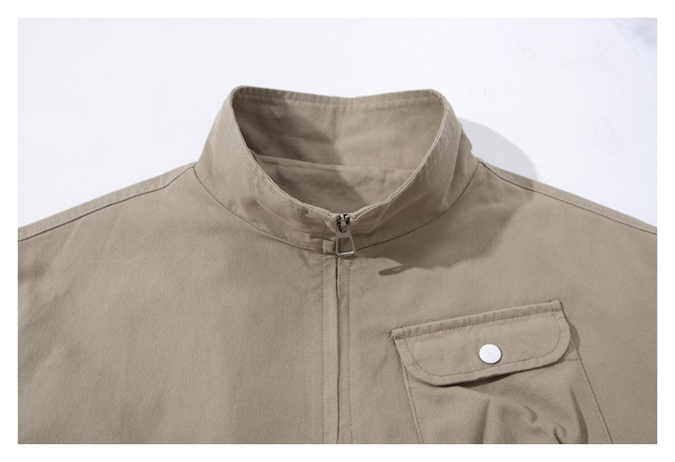Close-up of a beige jacket's stand collar, front zipper, and snap-flap chest pocket.