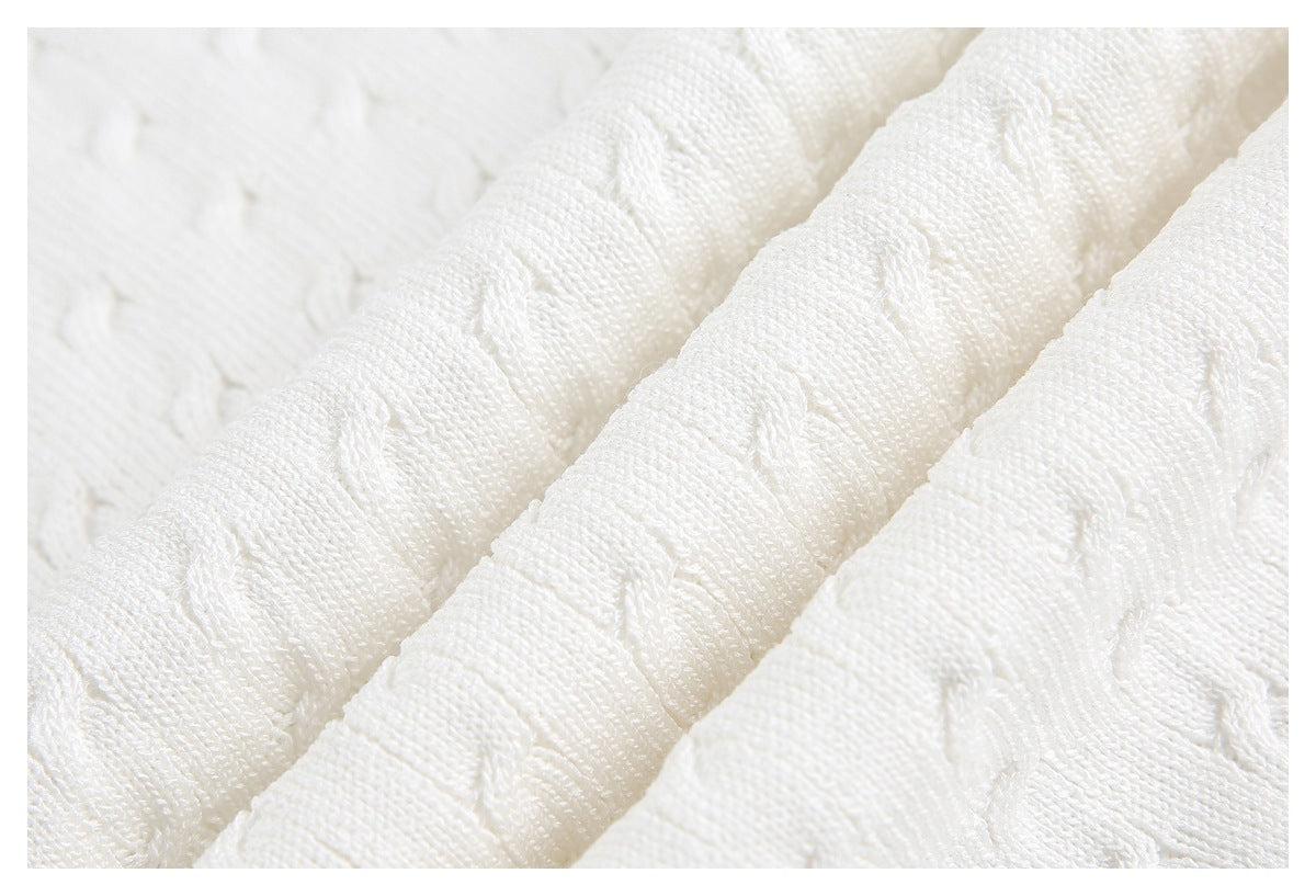 Macro view of white knit fabric showing raised cable-like texture and folded ridges.