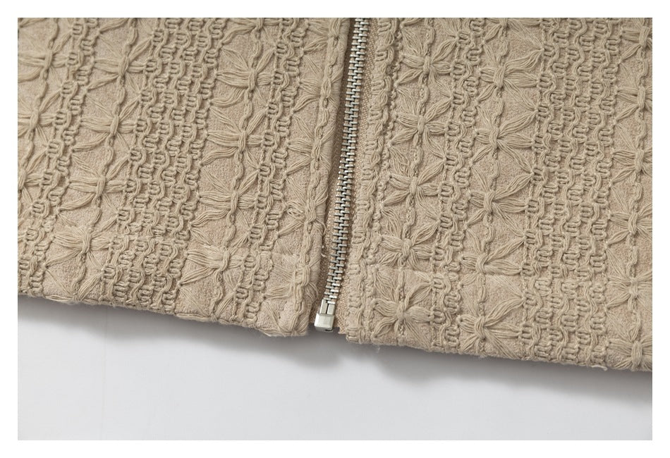 Close-up of a vertical silver zipper between panels of beige fabric with raised floral stitching.