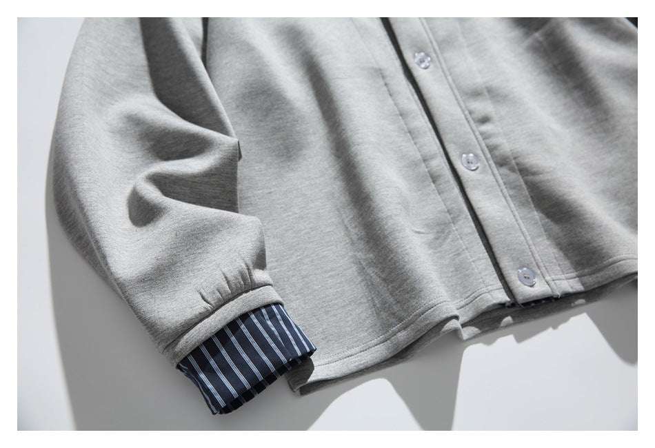 Close-up of the gray jacket sleeve and hem, with a blue striped cuff peeking from beneath the sleeve.