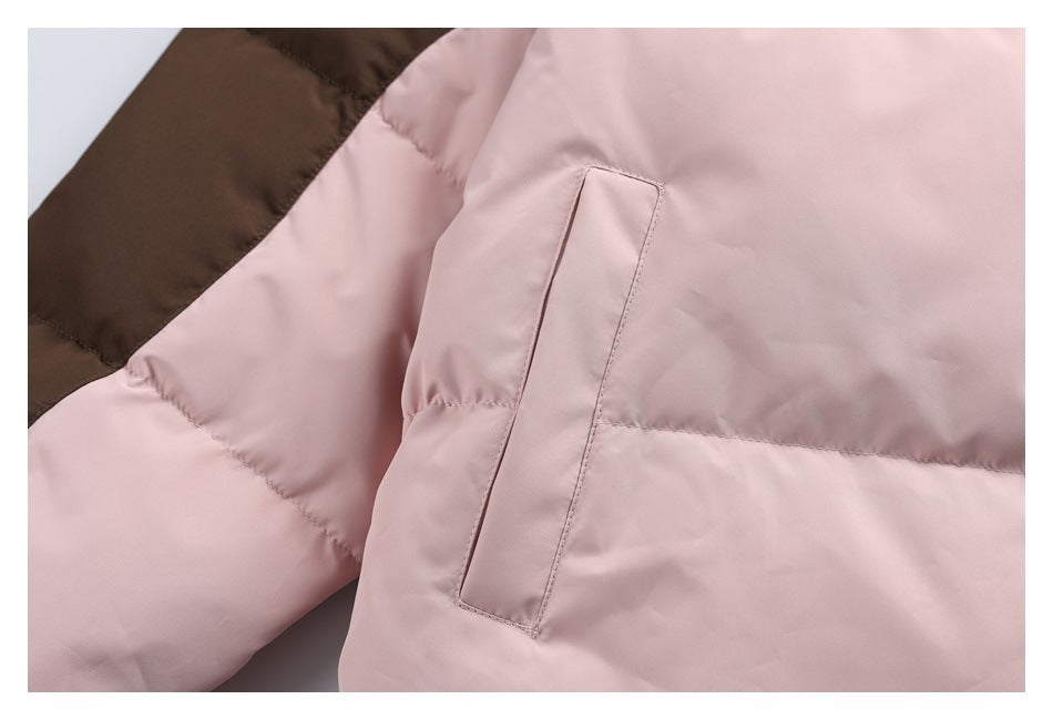 Close-up of a pale pink jacket pocket opening beside a brown color-block sleeve panel.
