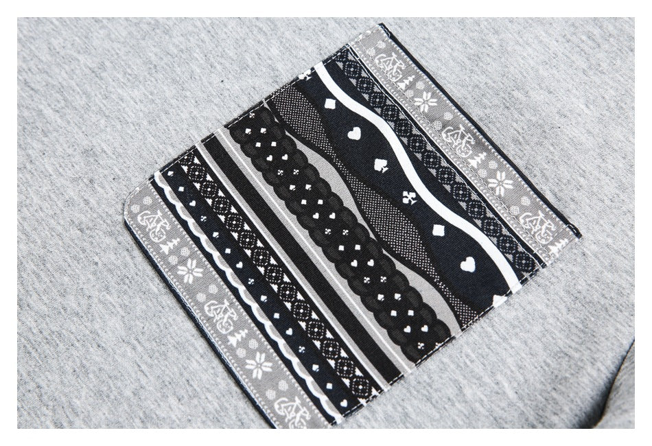 Close-up of a rectangular black, white, and gray patterned pocket sewn onto light gray fabric.