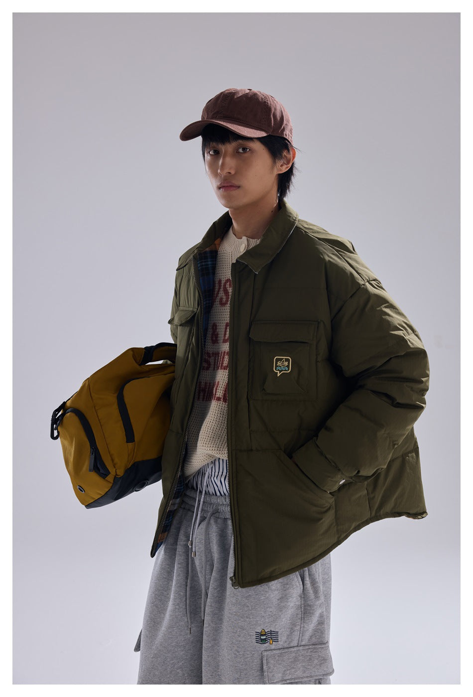 Model in a three-quarter view wearing an olive quilted jacket with plaid lining and flap pockets.