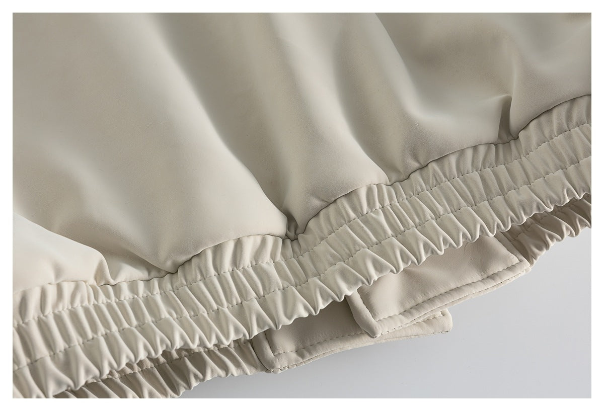 Close-up of the ivory coat's gathered elasticized hem and layered lower panels.