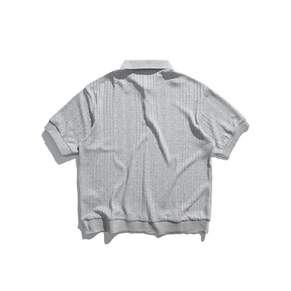 Back view of a light gray short-sleeve ribbed polo shirt with a collar and ribbed cuffs and hem.
