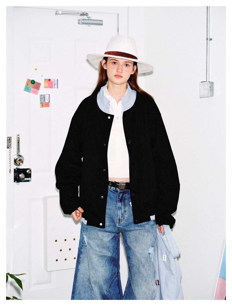 Front view of a model in a black snap-front jacket with roomy sleeves and a striped shirt collar showing.