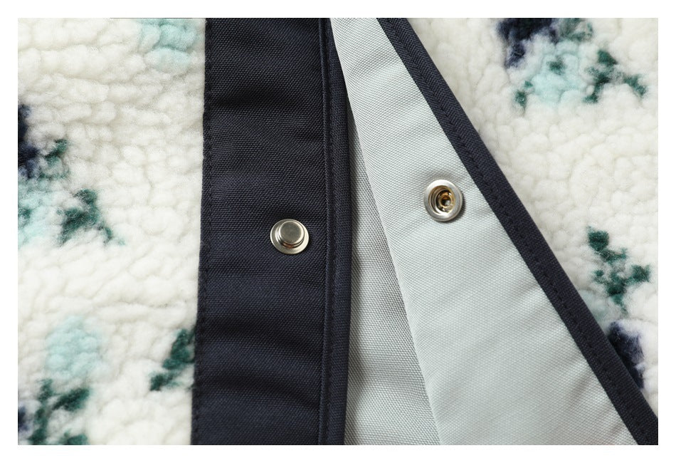Close-up of two metal snap fasteners on dark binding beside the ivory floral plush fabric.