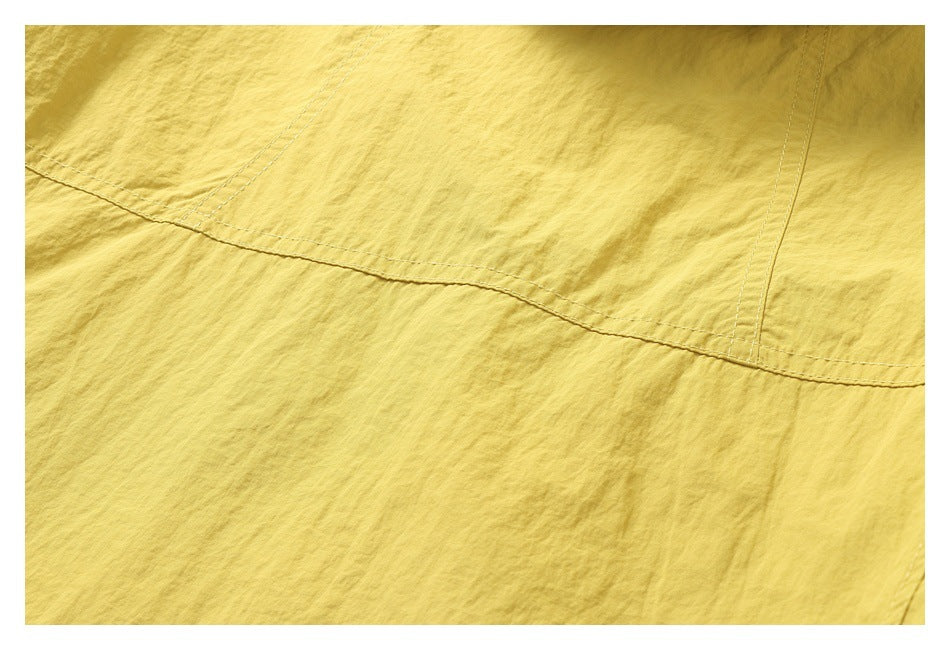 Close-up of mustard-yellow garment fabric with curved double-stitched panel seams.