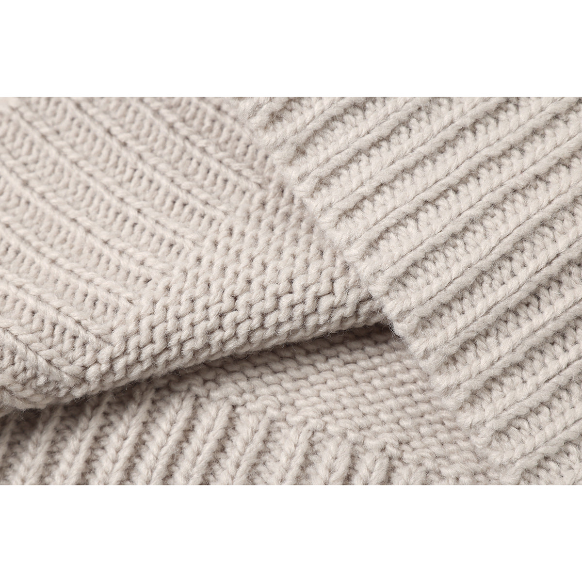 Extreme close-up of the cream sweater's textured knit stitches and ribbed seam.