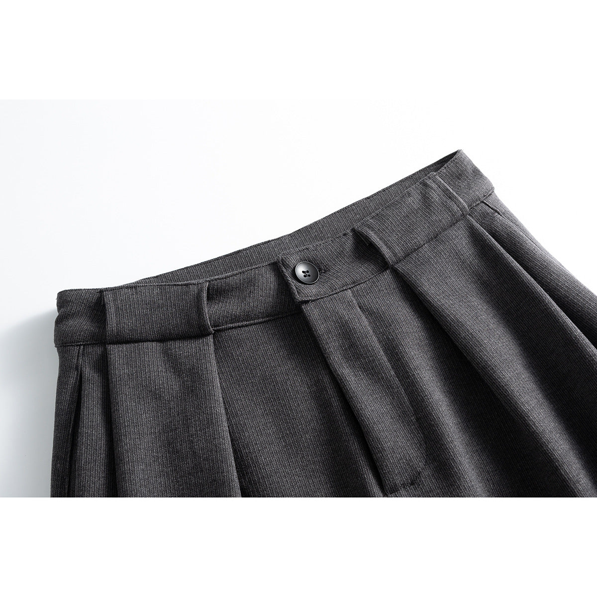 Close-up of charcoal gray wide-leg trousers showing the buttoned waistband and front pleats.
