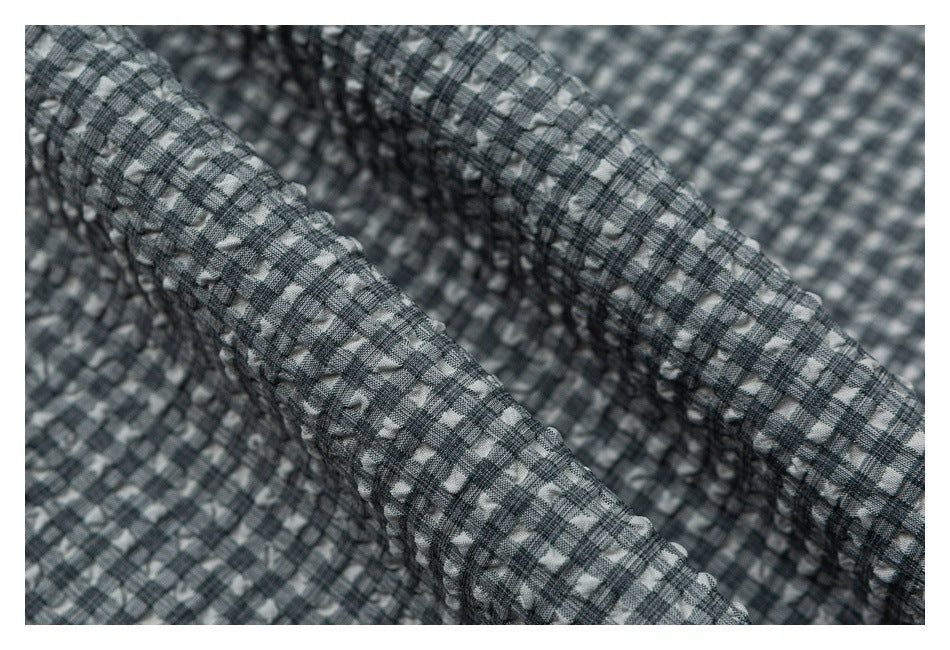 Close-up of gray, black, and white checkered fabric gathered into soft folds.