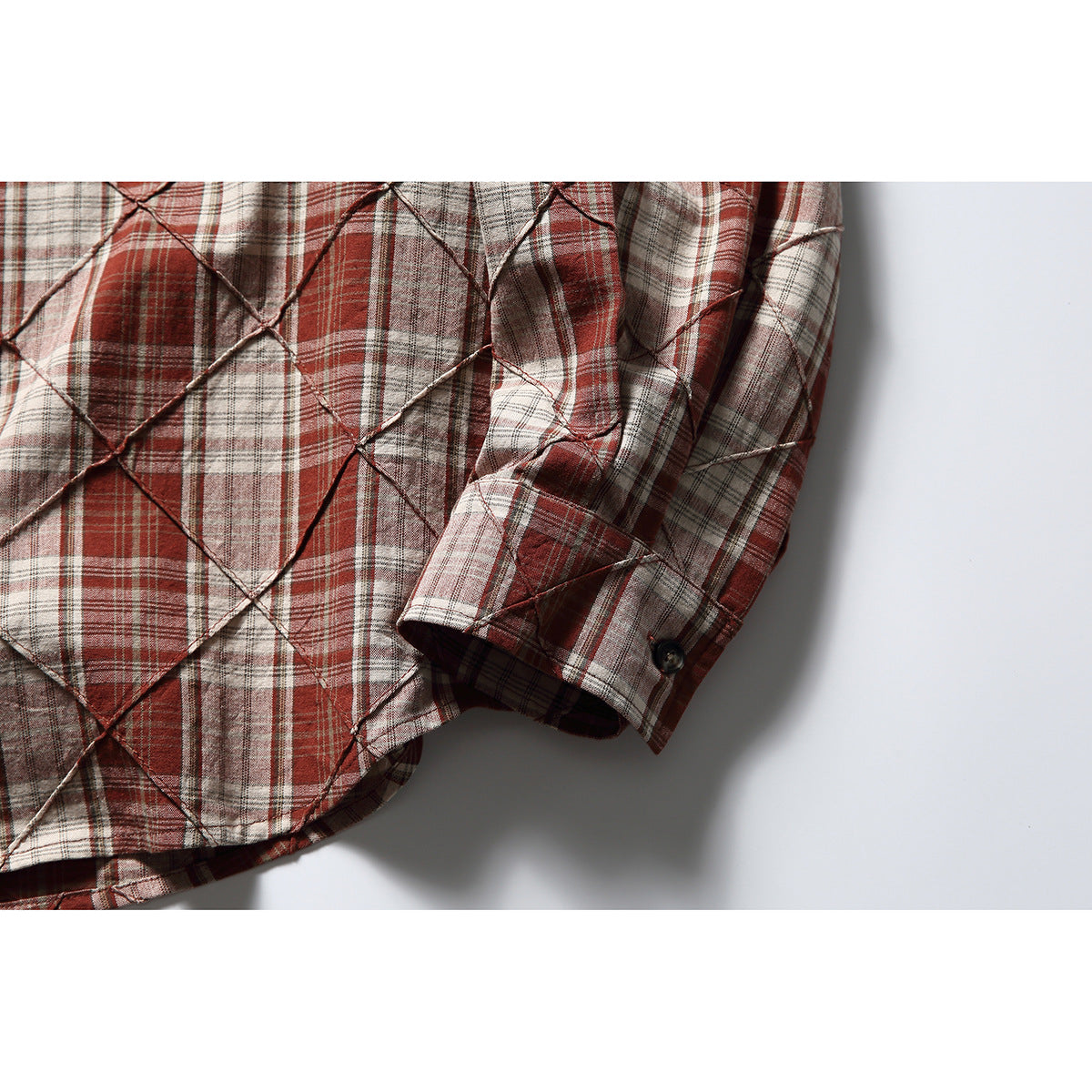 Close-up of the plaid shirt’s sleeve, cuff, button, and raised diamond stitching.
