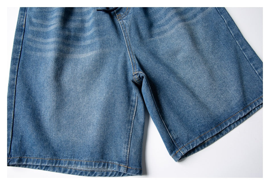 Cropped flat-lay view of blue denim shorts showing the front crotch seam and wide legs.