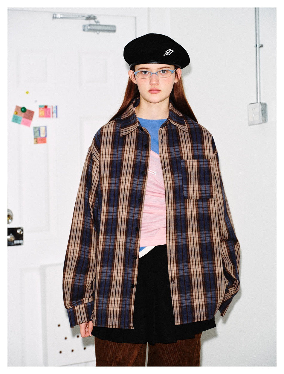 Close view of a model wearing an oversized blue, brown and beige plaid button-up shirt with a chest pocket.
