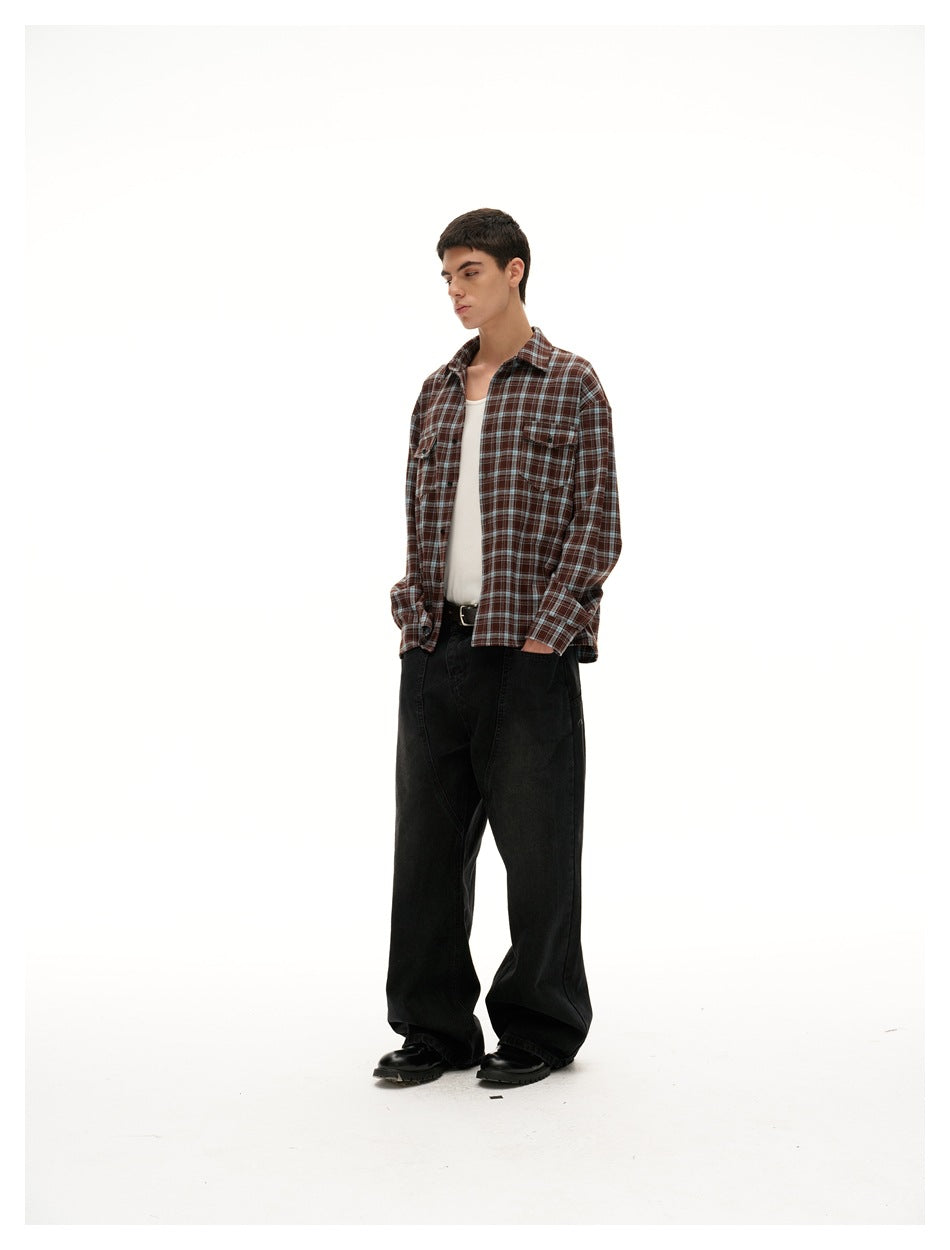 Three-quarter side view of a model in a brown plaid shirt, white tank, loose black trousers, and black shoes.