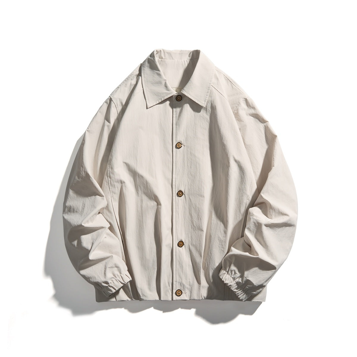 Off-white button-front jacket with pointed collar, elastic cuffs and light brown buttons, flat lay