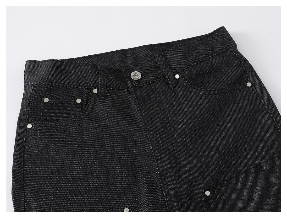 Close-up of the front waistband and pockets of black denim pants, with a button and metal rivets.
