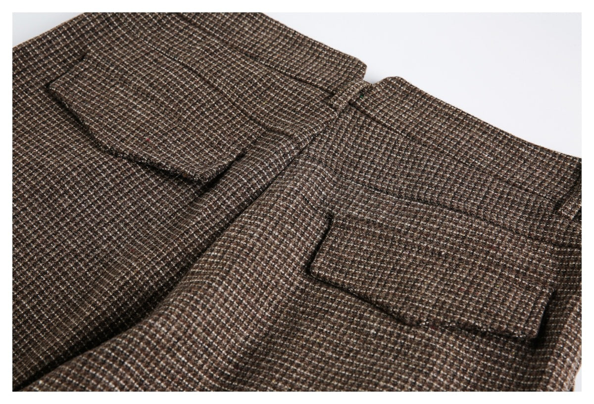 Close-up of brown small-check fabric with two rectangular flap pockets and visible stitching.