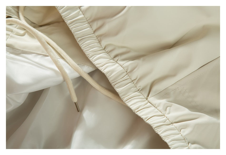 Close-up of ivory gathered elastic fabric and a matching drawstring with a metal tip.