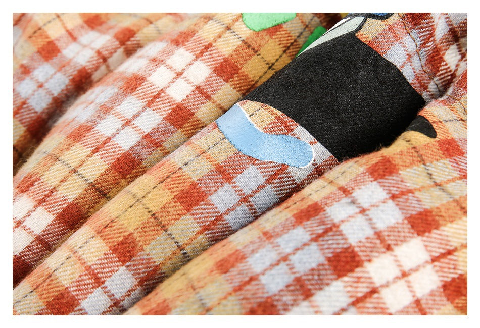 Close-up of a colorful printed graphic detail on orange, cream and pale blue plaid fabric.