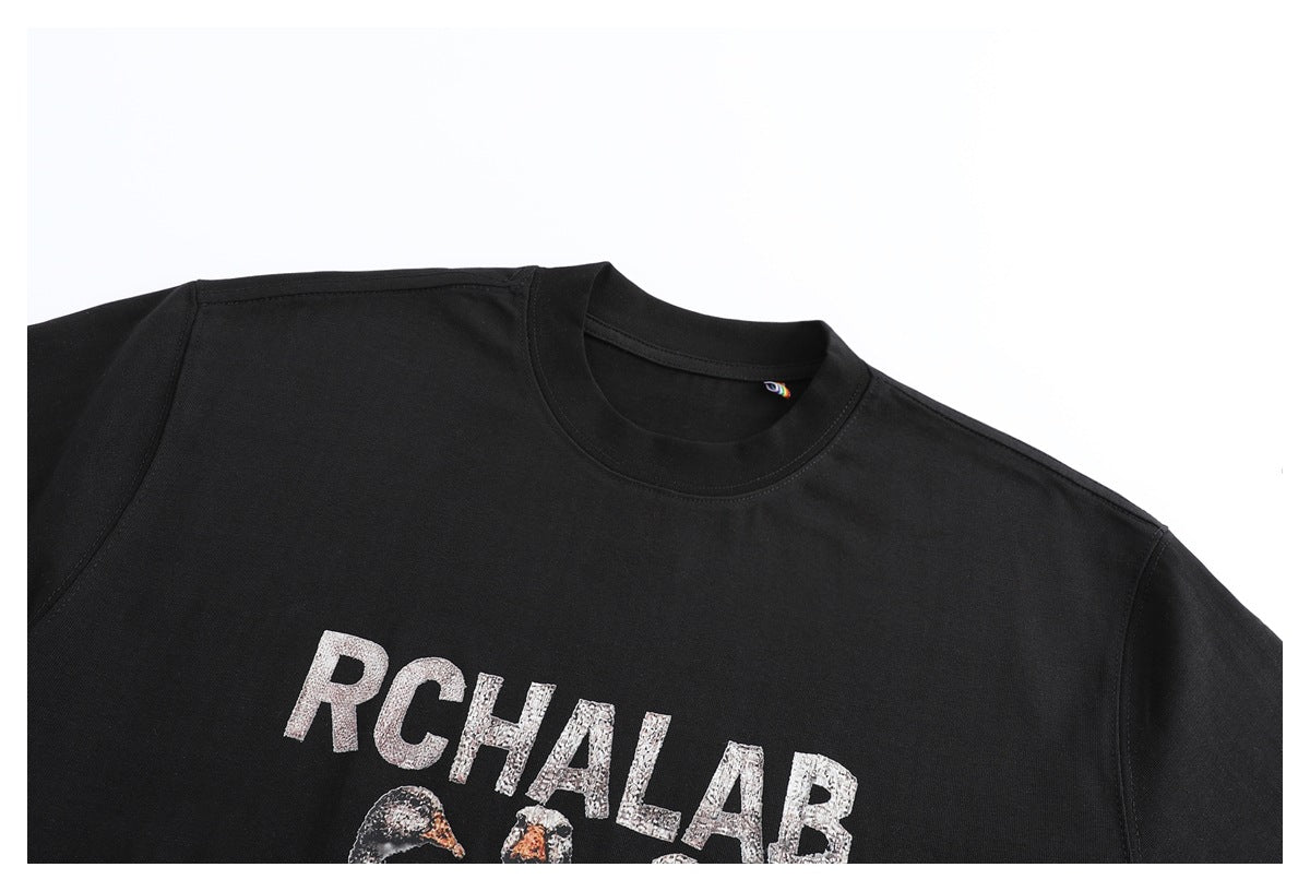 Close-up of a black crew-neck T-shirt with RCHALAB lettering and part of a bird graphic.