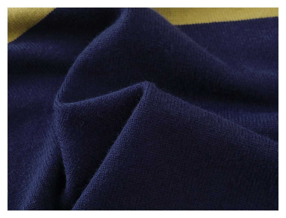 Close-up of dark navy knit fabric gathered in folds, with a mustard-yellow section at the top.