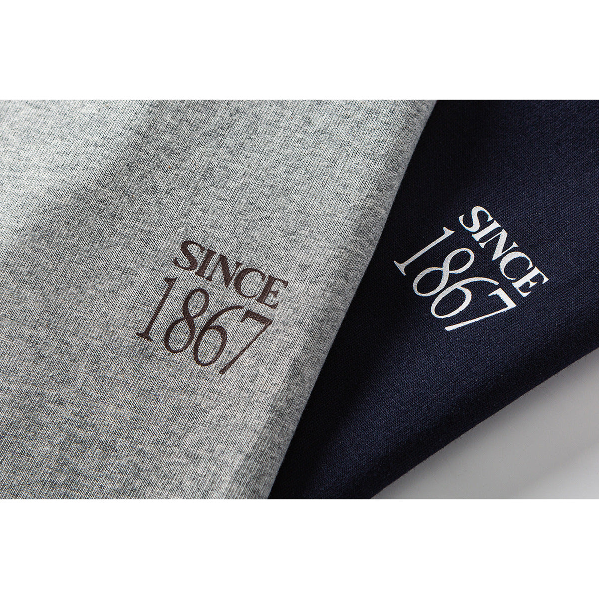 Close-up of gray and navy T-shirt fabric with “Since 1867” printed on both colorways.