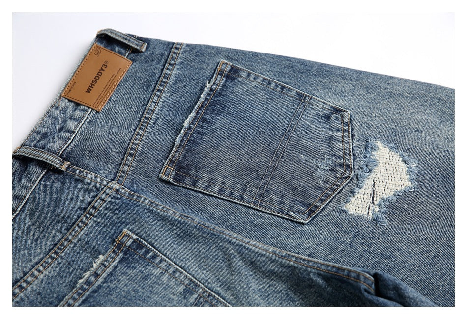 Close-up of the back pocket and leather waistband patch on distressed blue jeans.