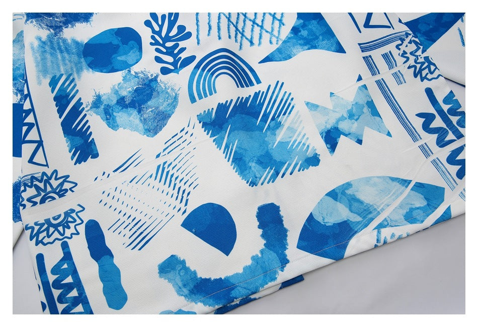 Close-up of the white shirt fabric covered in varied abstract blue shapes and brush-like patterns.