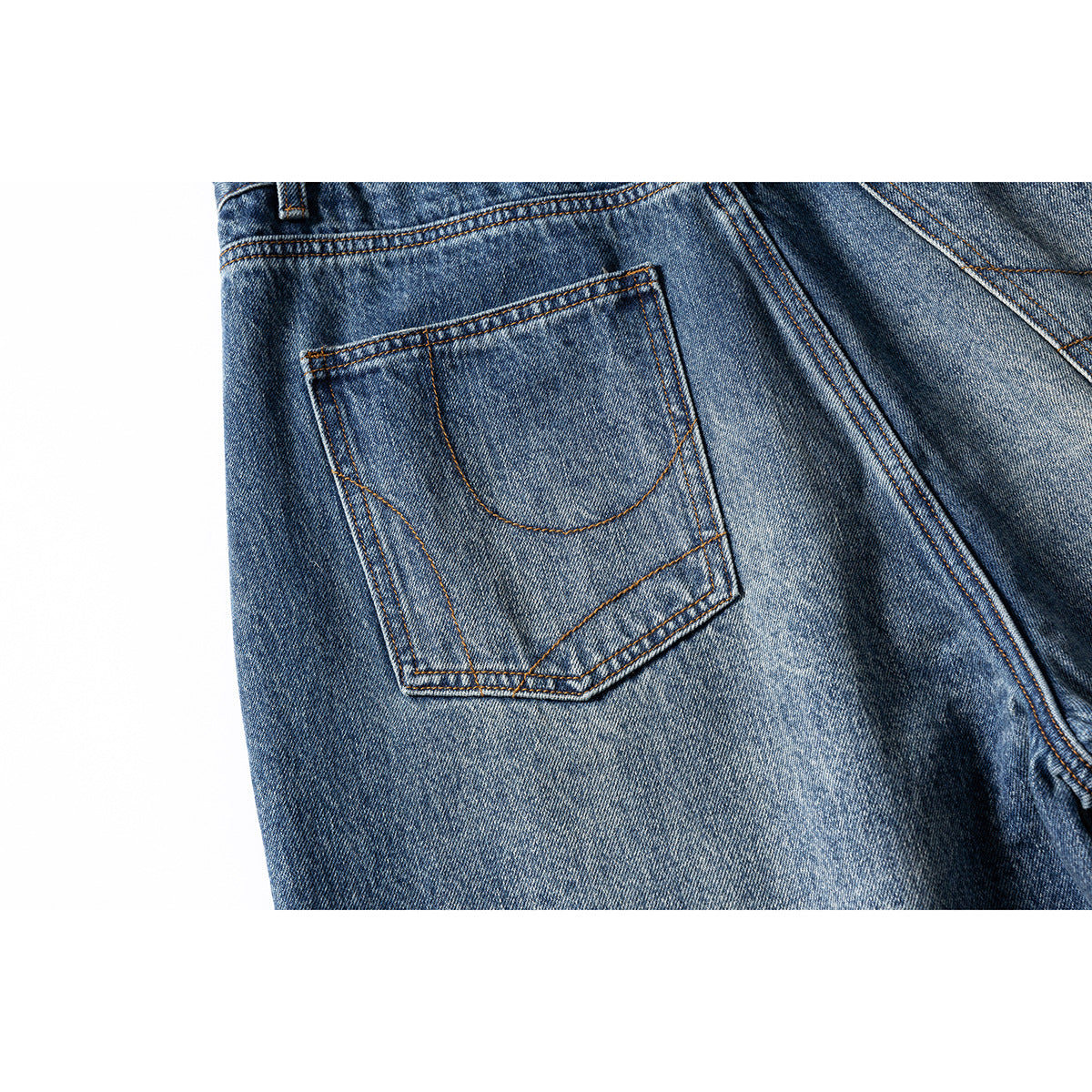 Close-up of a back patch pocket on blue washed jeans with contrasting stitching.