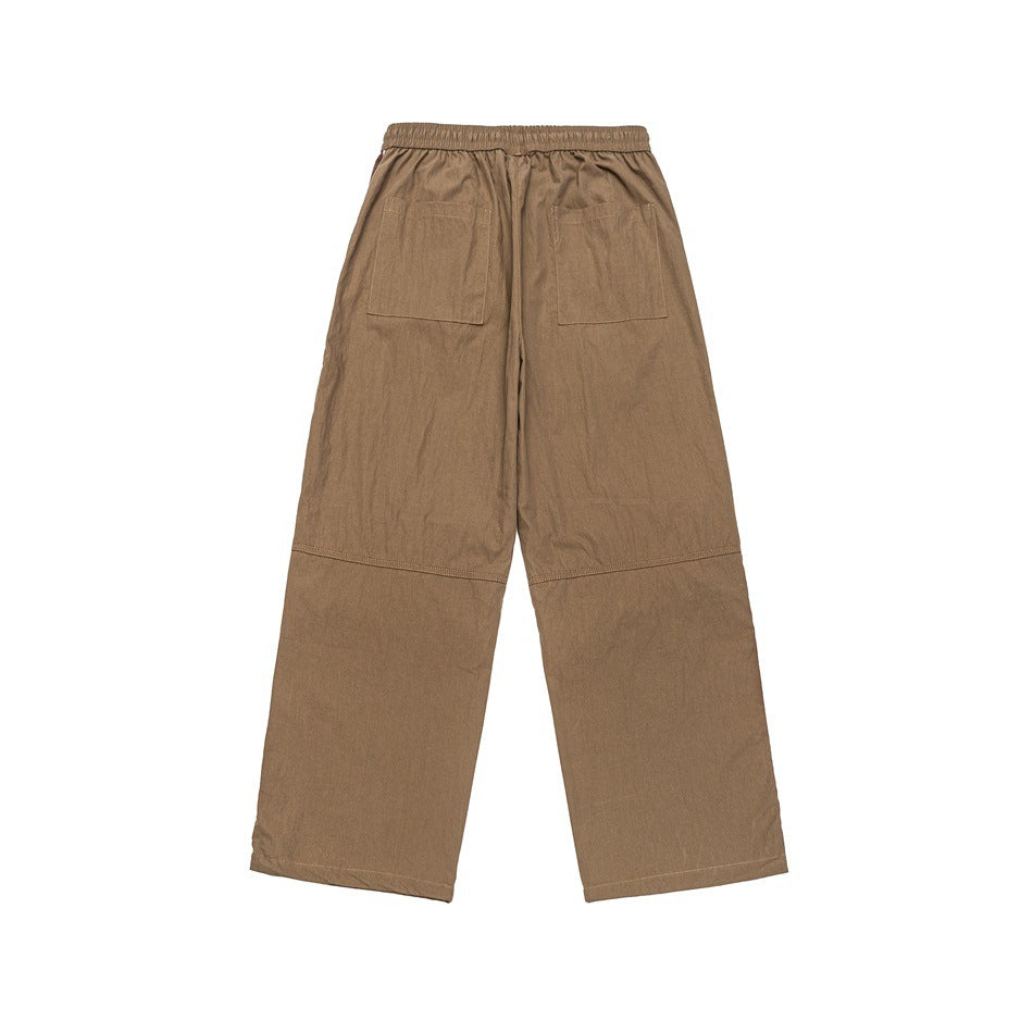 Back view of tan wide-leg pants with an elastic waistband, two patch pockets, and seam details.
