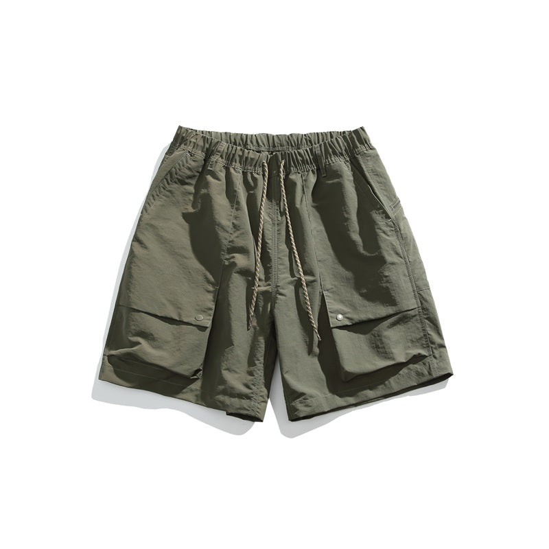 Army green drawstring shorts with elastic waist and large snap flap front pockets, flat lay front view