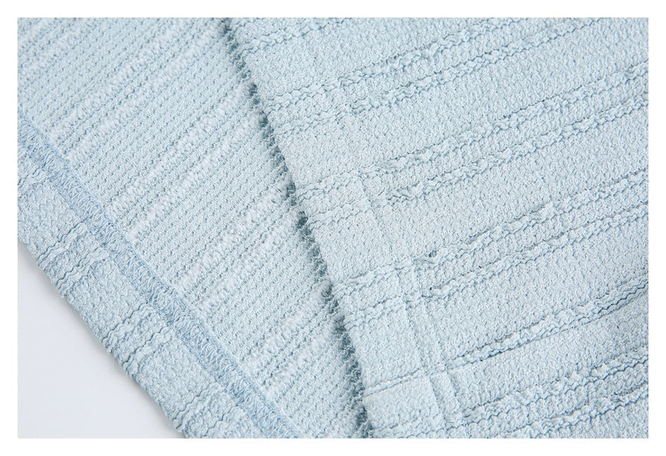 Close-up of the pale blue garment's textured knit and stitched seam.