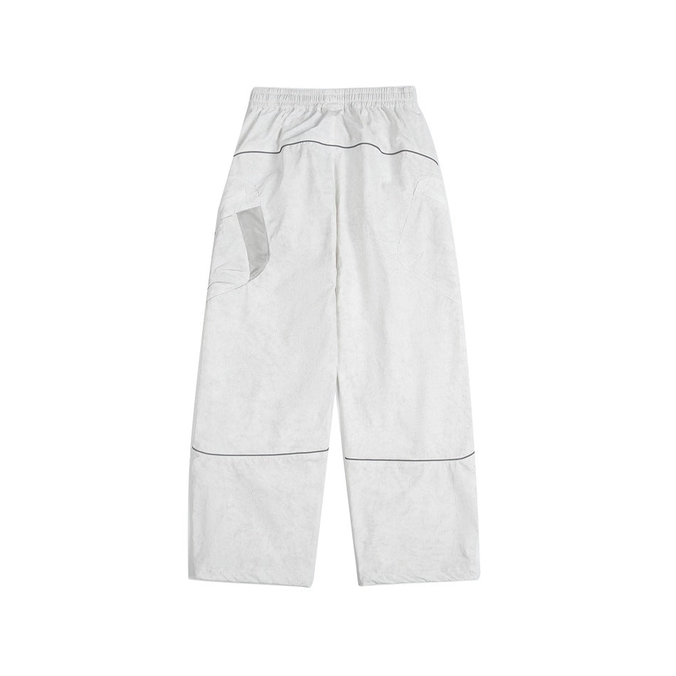 Back view of loose white cargo pants with curved pockets and dark piping across the seat and lower legs.