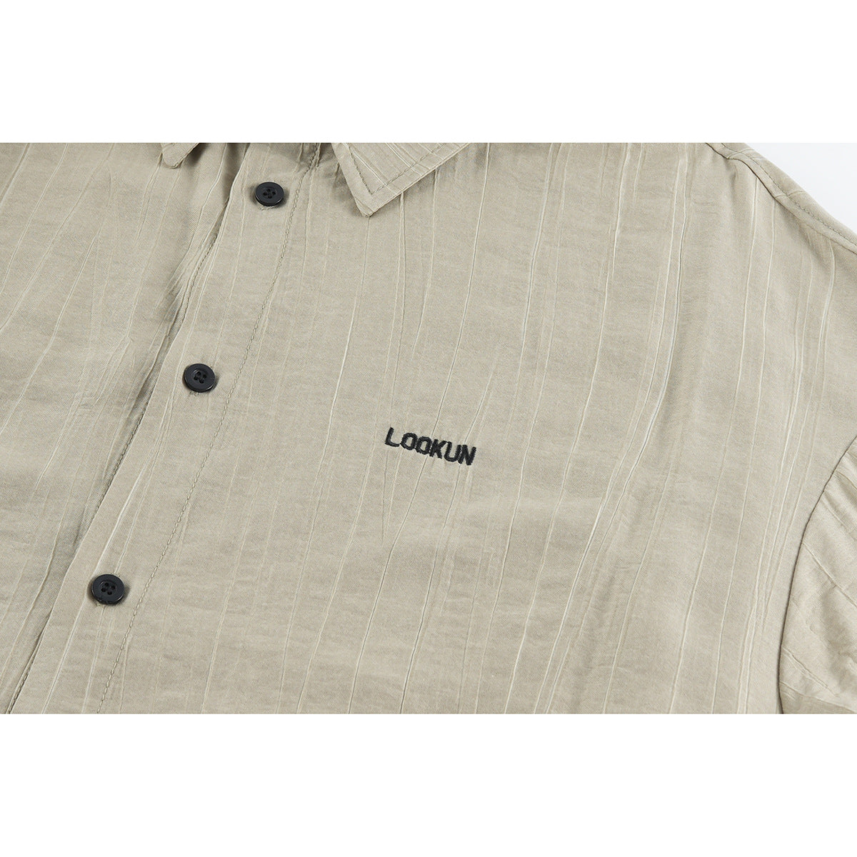 Close-up of a beige pinstriped shirt front with dark buttons and small black embroidered lettering.