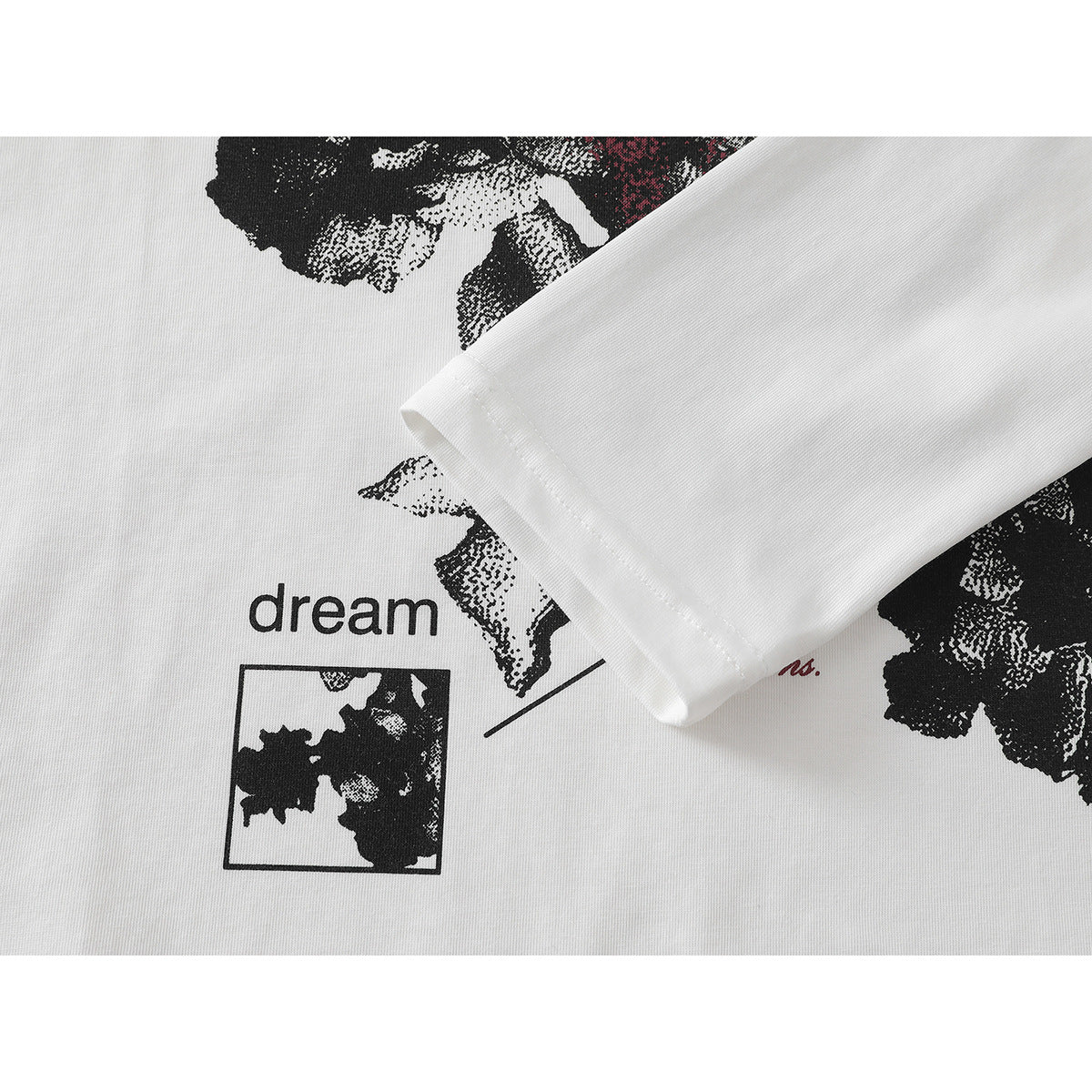 Close-up of a white T-shirt with black floral artwork, red accents and the word “dream.”