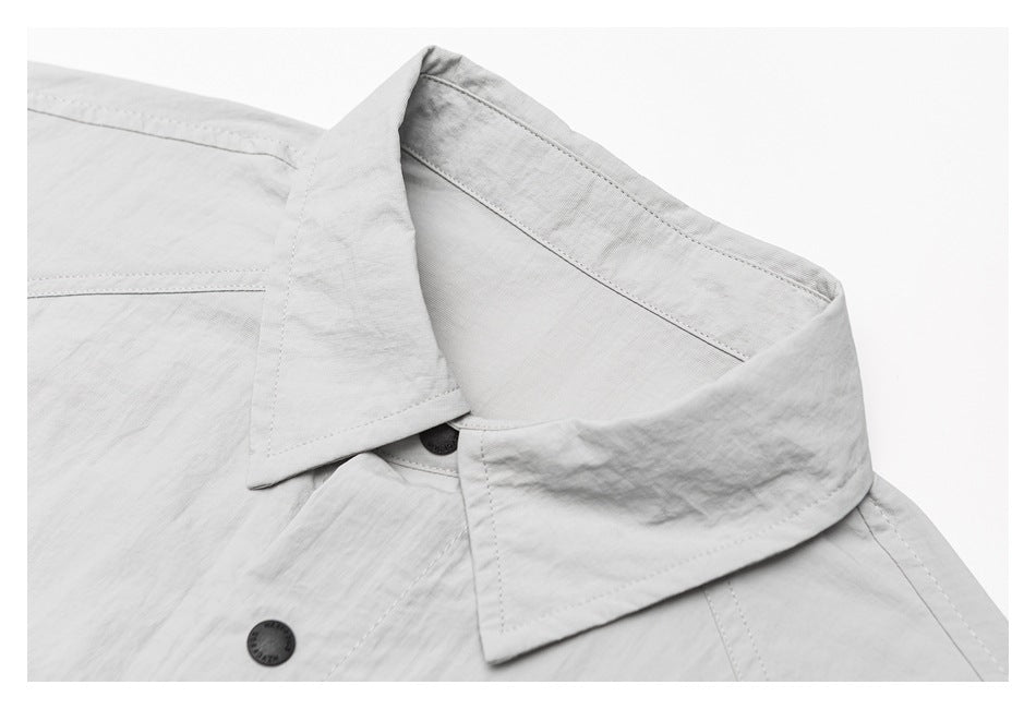 Close-up of the light gray shirt’s pointed collar, inner collar, and front button.