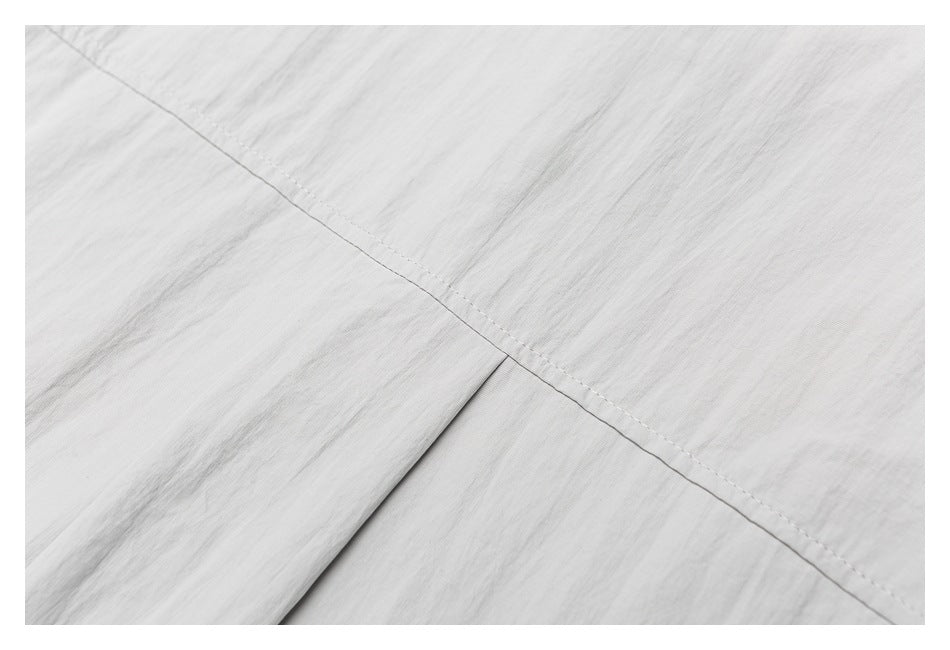 Close-up of light gray fabric with a diagonal stitched seam and a folded edge.