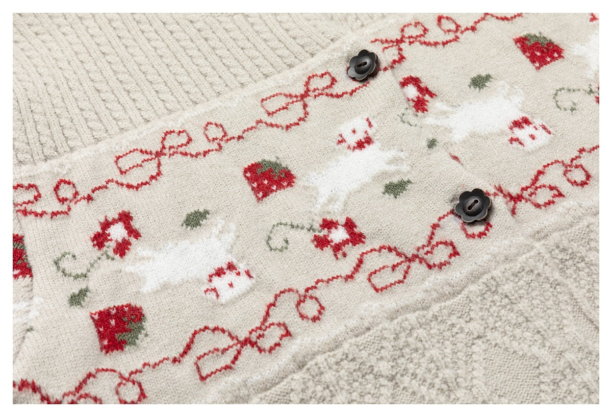 Close-up of a cream knit cardigan with red bow and strawberry motifs, small animal designs, and dark buttons.