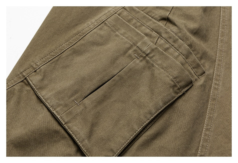 Close-up of an olive-brown cargo trouser pocket with a flap, stitching and side seam.
