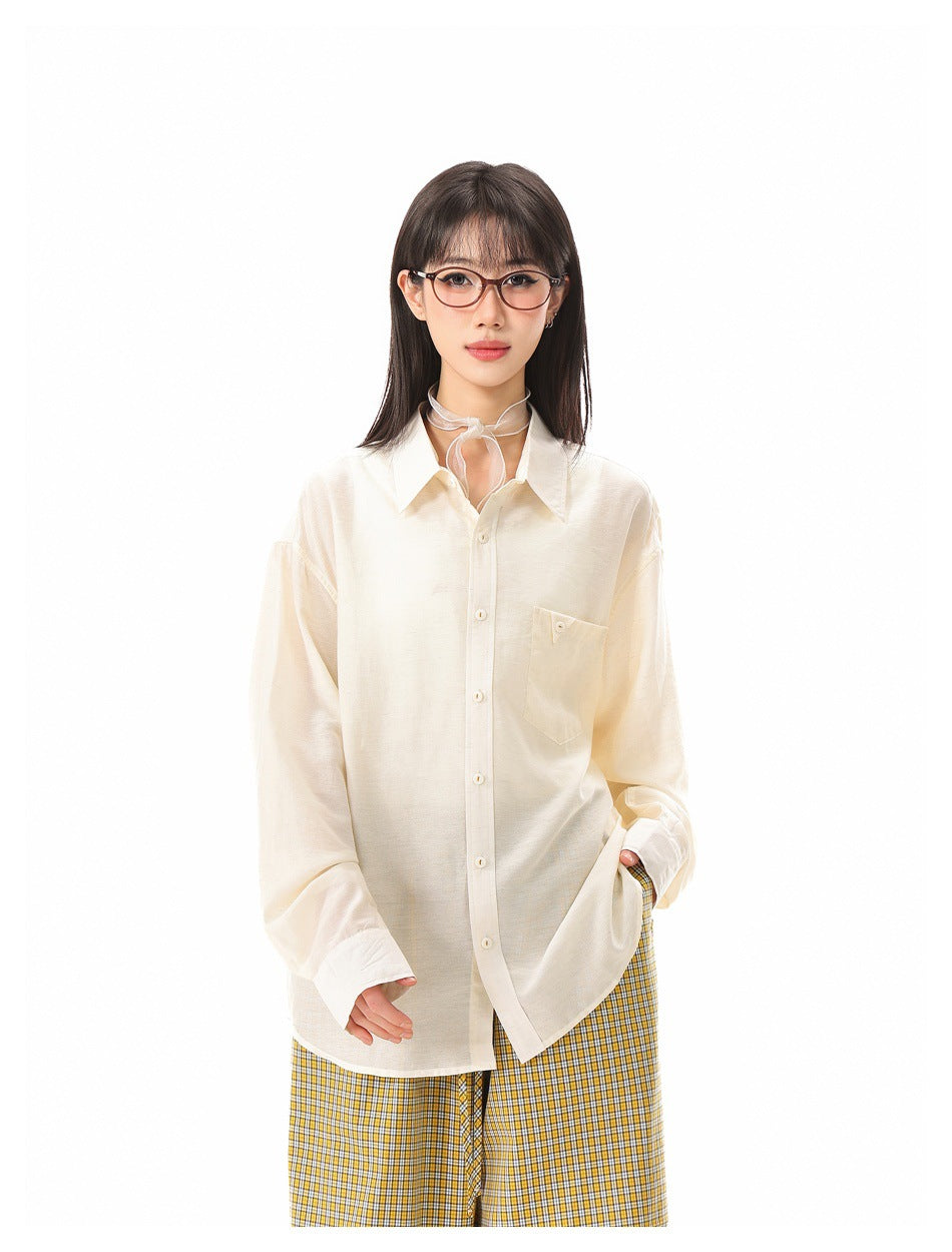 Model wearing an oversized ivory button-up shirt with a chest pocket and yellow plaid trousers.